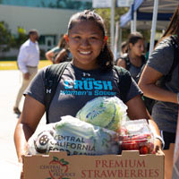 Student smiling and holding box of food