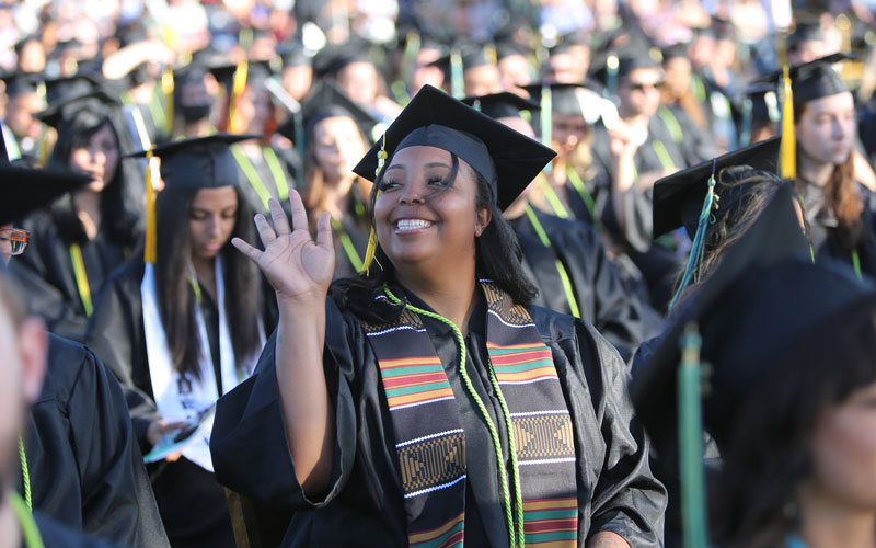 Graduate wearing cap and gown and waving