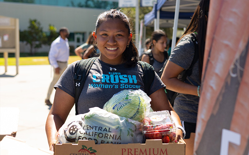 Student smiling and holding box of food