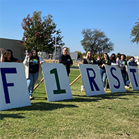 Students holding a sign that says "FIRST"