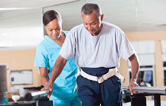 Occupational therapist helping an old man walk