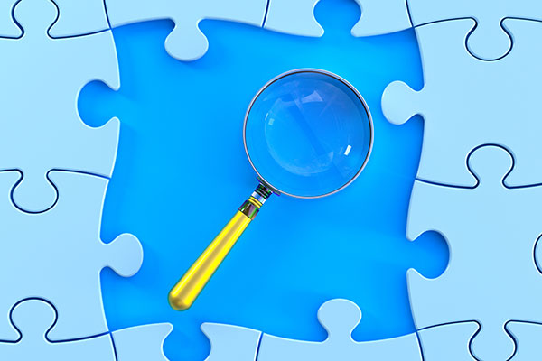 blue jigsaw puzzle pieces with a magnifying glass