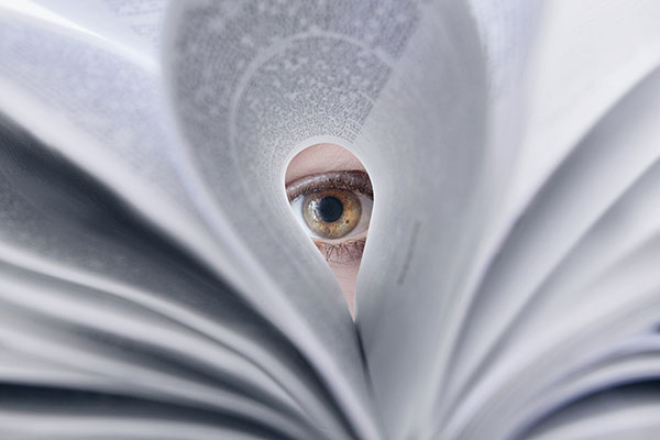 an eye peeking through the pages of a book